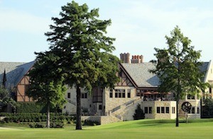 Country club on large grassy lawn with trees in the yard